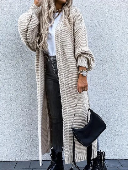 Close-up of a woman wearing a beige long cardigan holding a black handbag