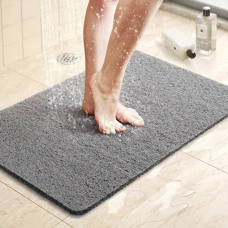 Feet standing securely on a grey non-slip shower mat under running water