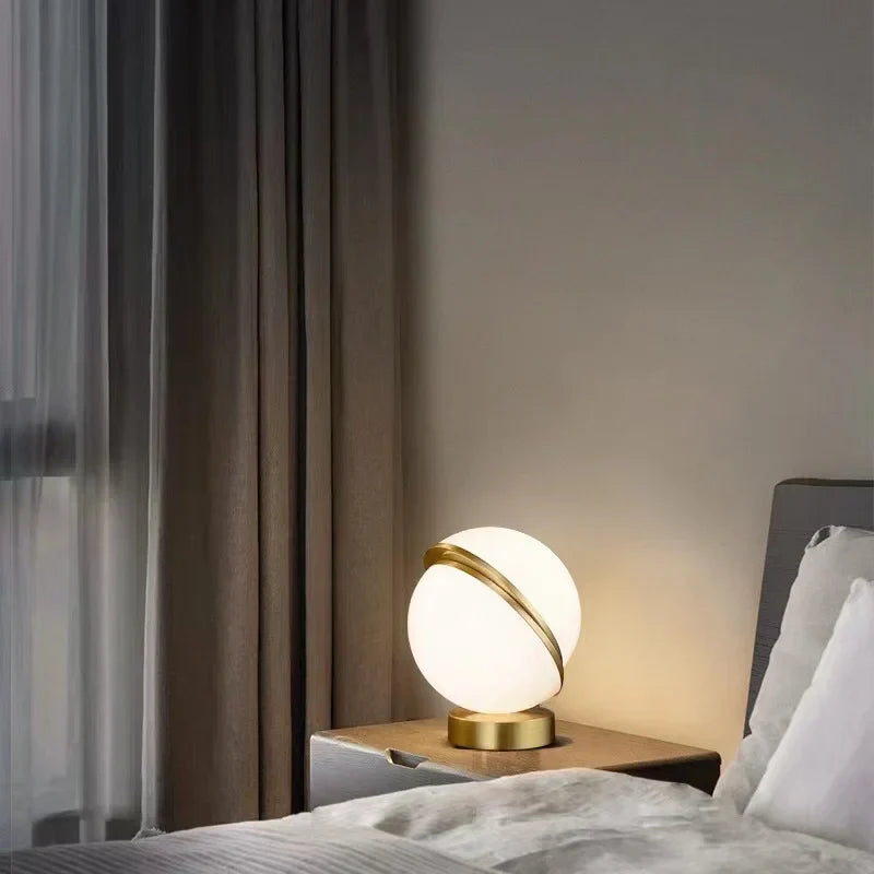Scandinavian white globe table lamp glowing on a bedside table next to a bed