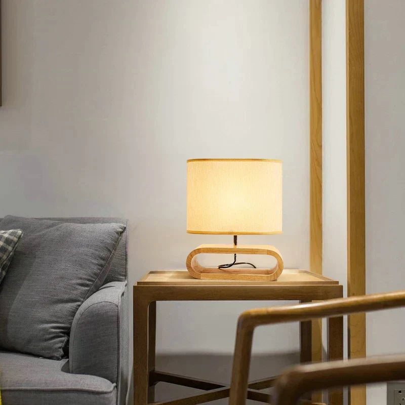 Wooden table lamp glowing on a side table next to a sofa in a living room.