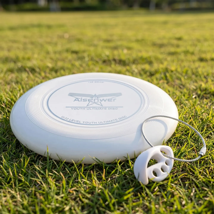 A white 175g flying disc resting on green grass with a disc clasp