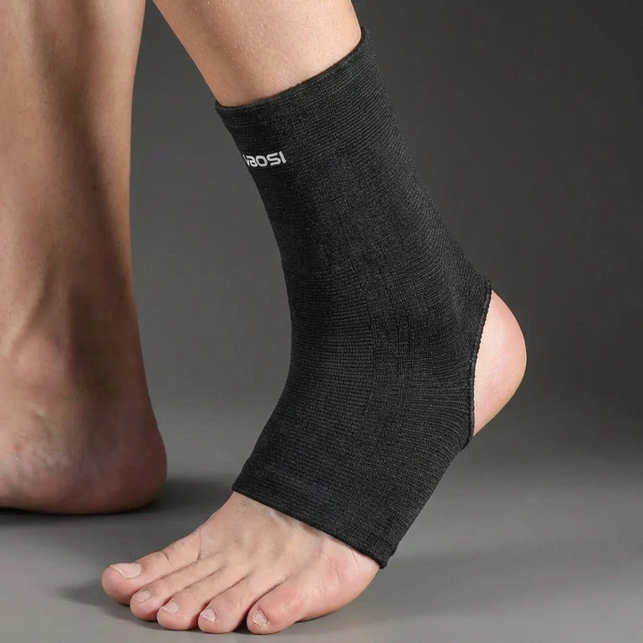Side profile of the black ankle support sleeve worn on the foot showing the heel cutout
