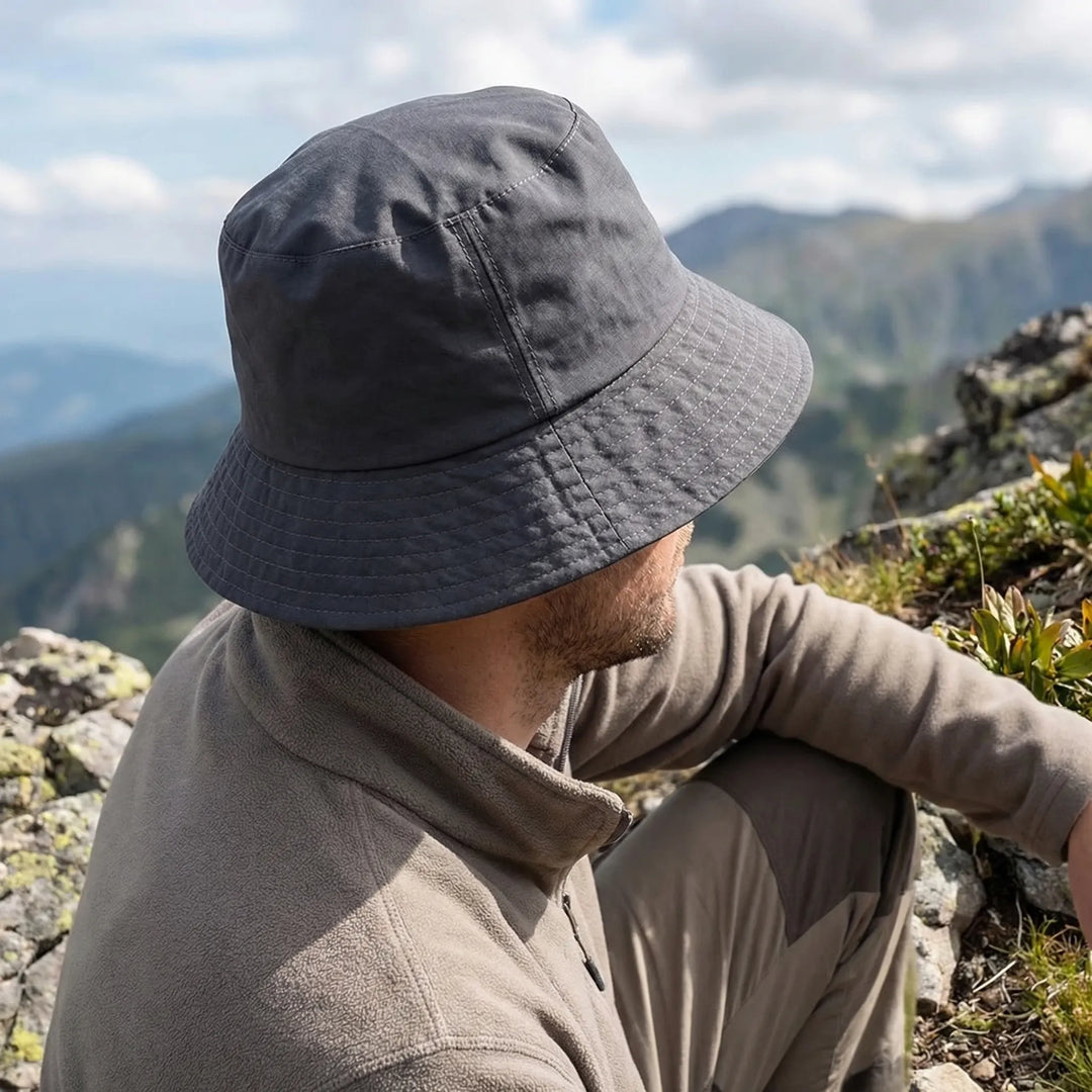 Man wearing a gray wide-brim water-repellent bucket hat outdoors in nature