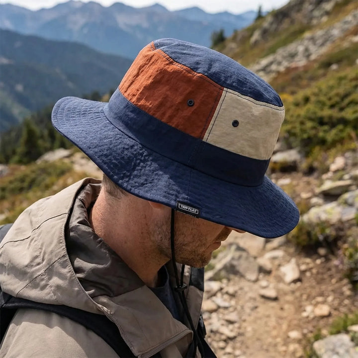 Man wearing a wide-brim outdoor sun hat with color-block panels during a hike