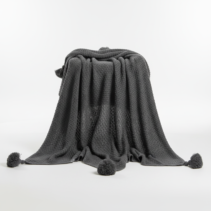 Soft knit blanket featuring a textured waffle pattern and stylish tassel fringe