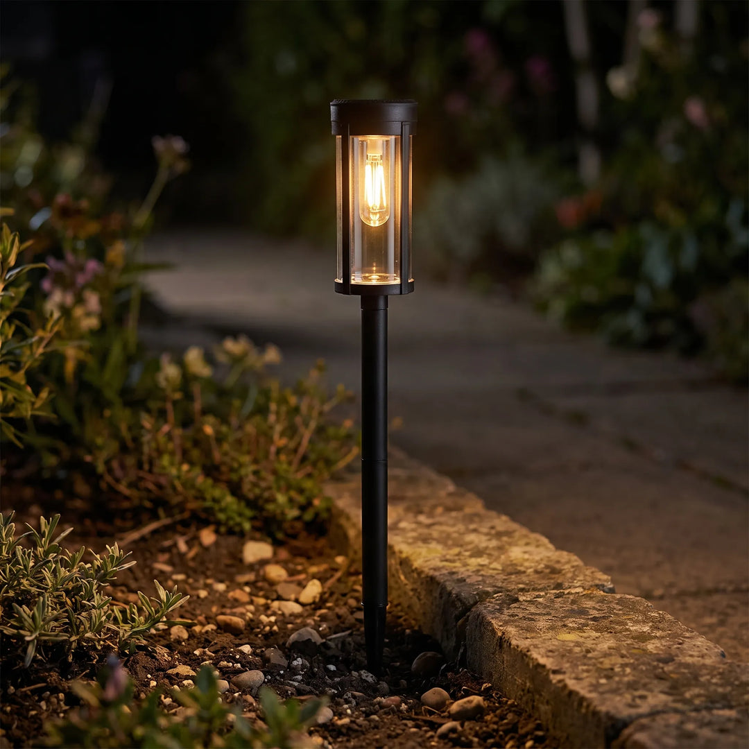 Retro solar pathway garden light illuminating a stone walkway at dusk