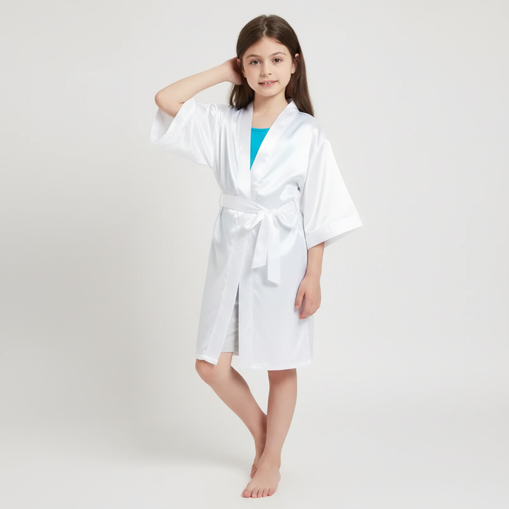 Little girl posing in a white satin kimono robe against a neutral background