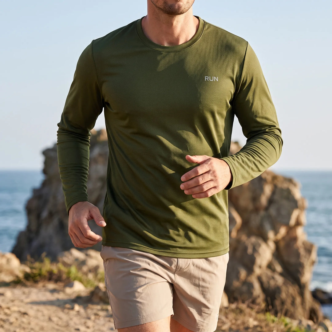 Man wearing an army green long sleeve athletic sun shirt outdoors near the ocean