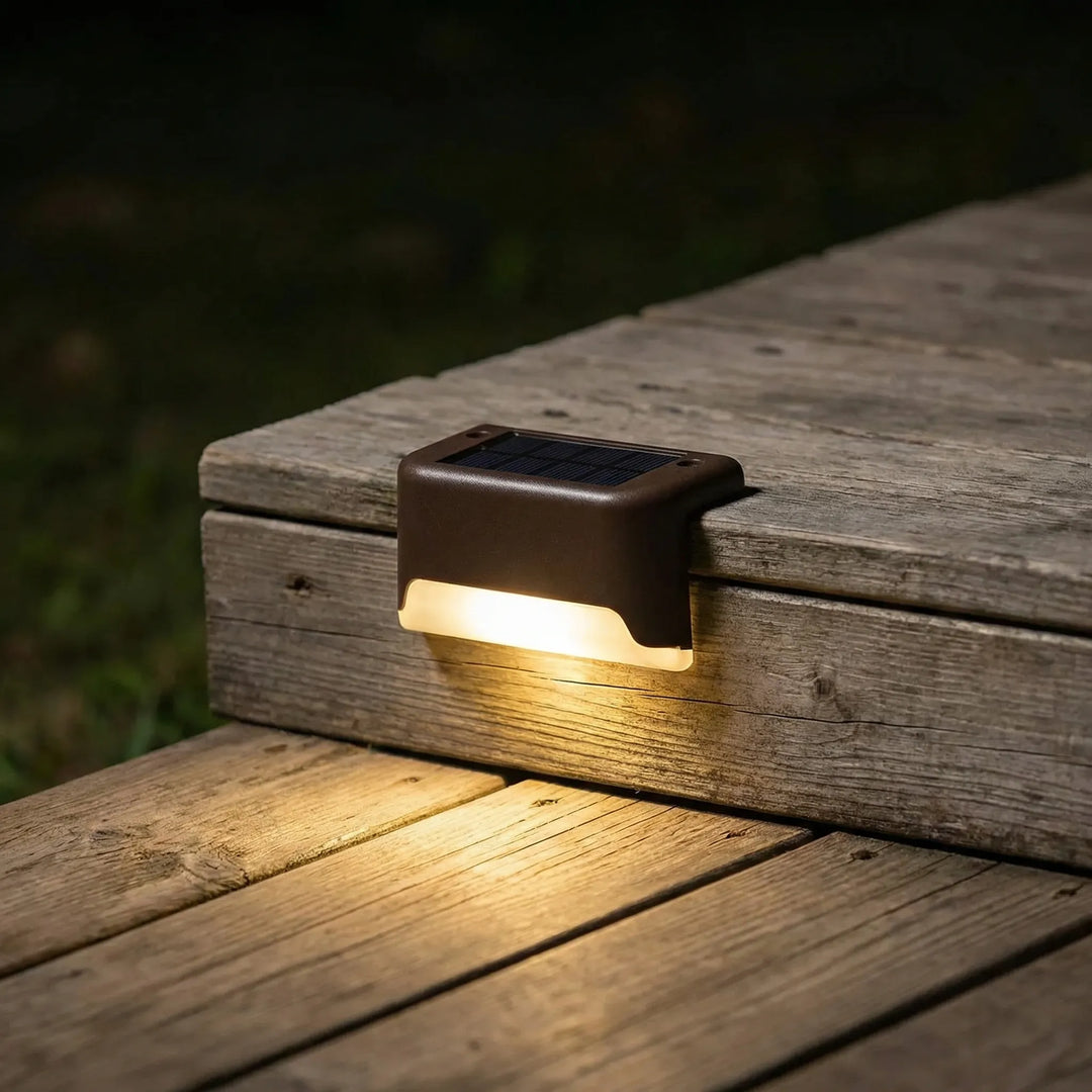 Solar-powered outdoor step light illuminating a wooden deck stair at night