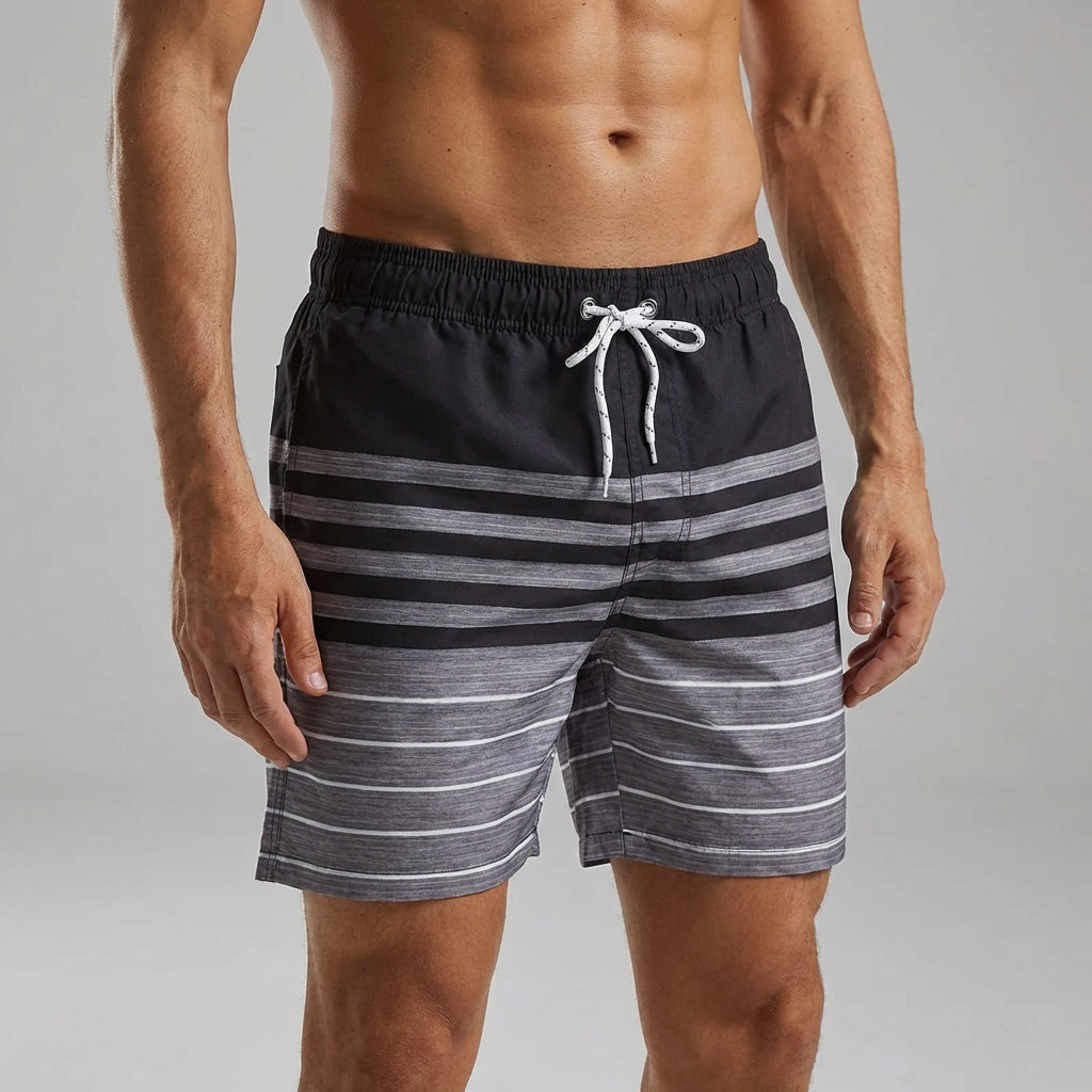 Man wearing black striped casual swim shorts on a neutral background