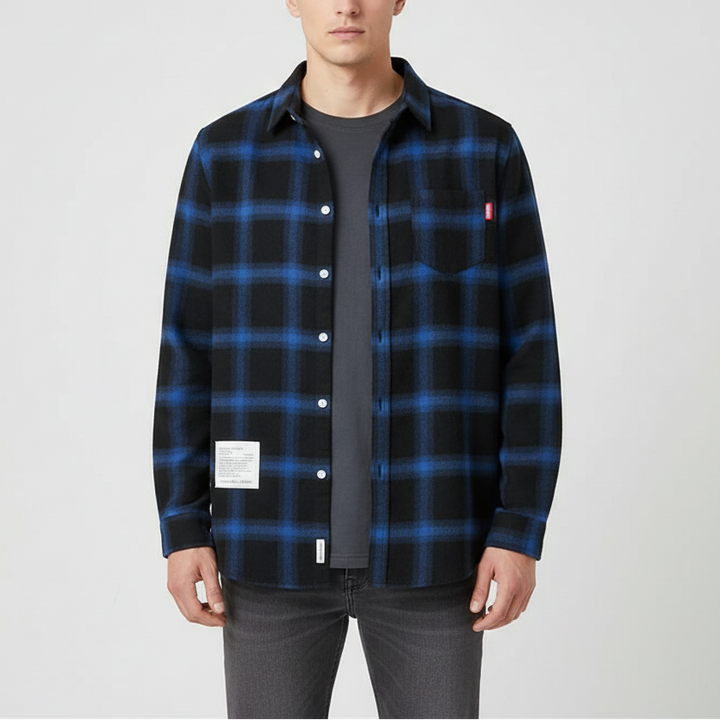Studio shot of man wearing blue and black plaid overshirt against neutral background