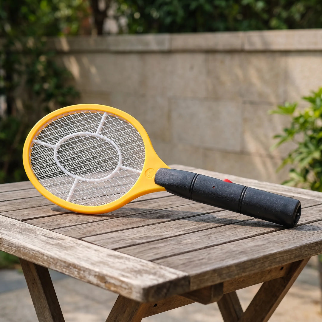 Yellow electric fly swatter resting on a wooden outdoor table