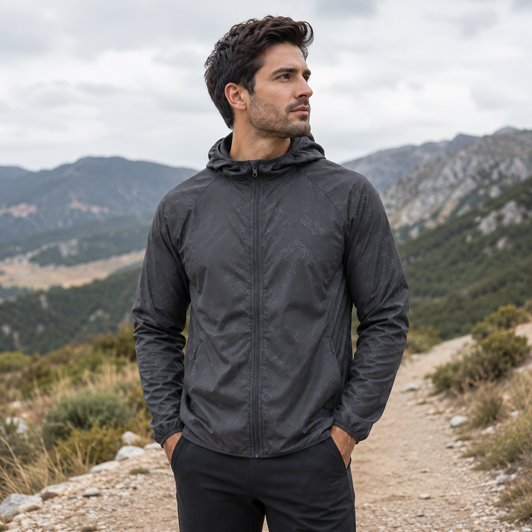 Man wearing a dark hooded windbreaker on a mountain trail