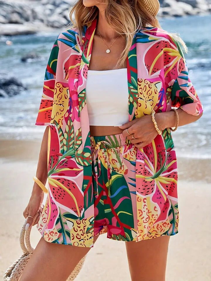 Woman wearing vibrant tropical printed kimono cardigan and high-waist shorts set at the beach