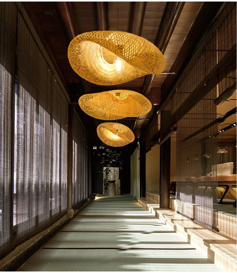 Multiple handwoven rattan pendant lamps suspended along a long hallway corridor