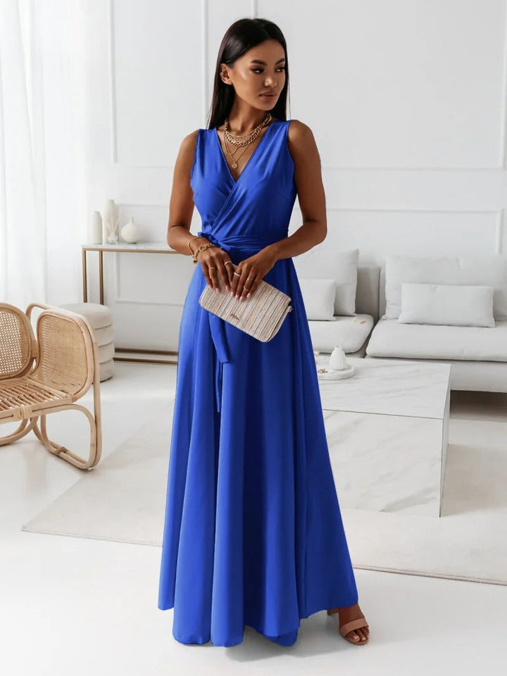 Woman wearing a vibrant blue sleeveless wrap maxi dress holding a clutch