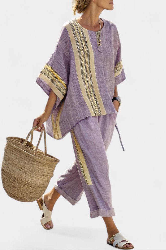 Woman wearing a purple contrast trim top and wide leg pants set while holding a straw bag