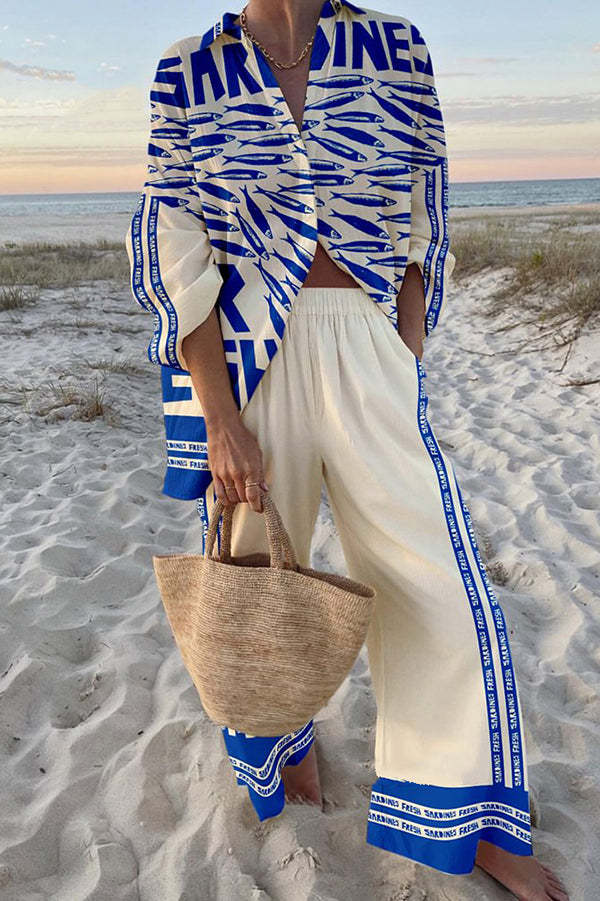 Model wearing a blue and white sardine patterned two-piece outfit on a sandy beach