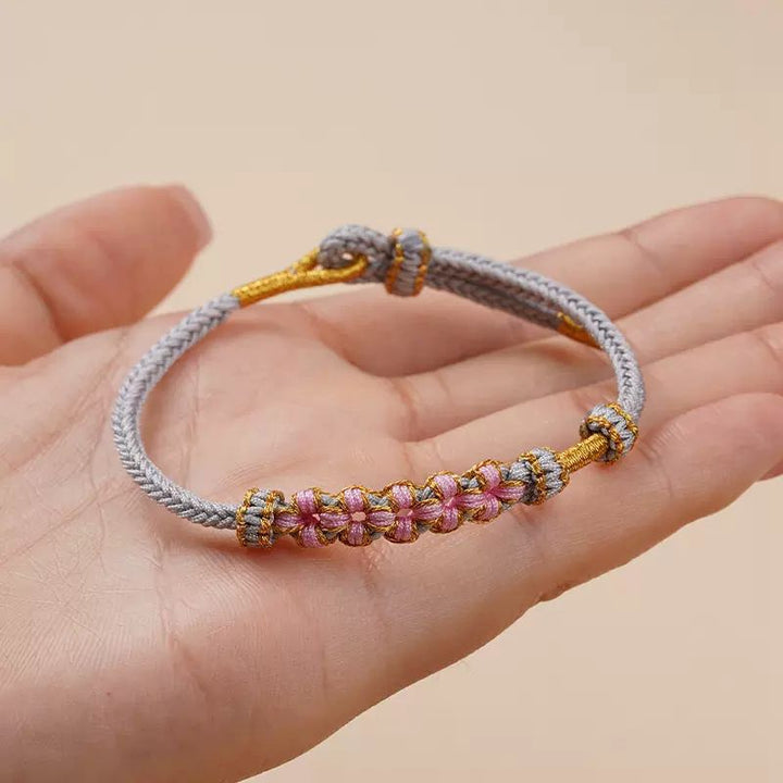 Grey blossom knot bracelet held in the palm of a hand