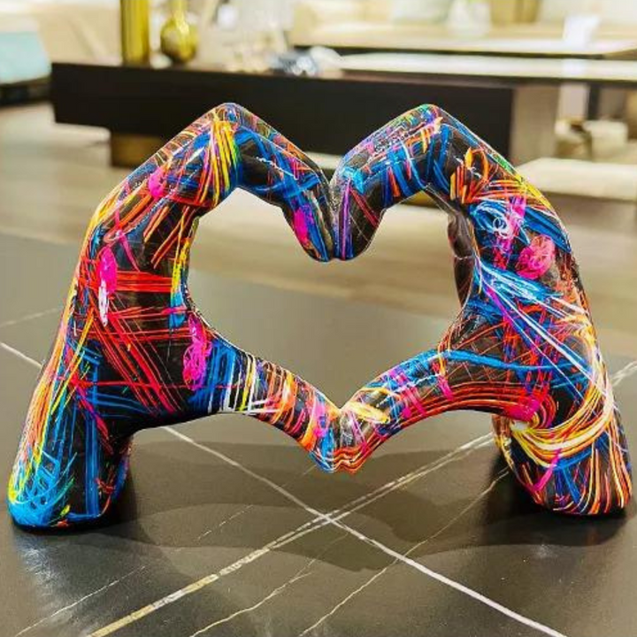 Colourful hand art sculpture shaped like a heart on a dark tabletop