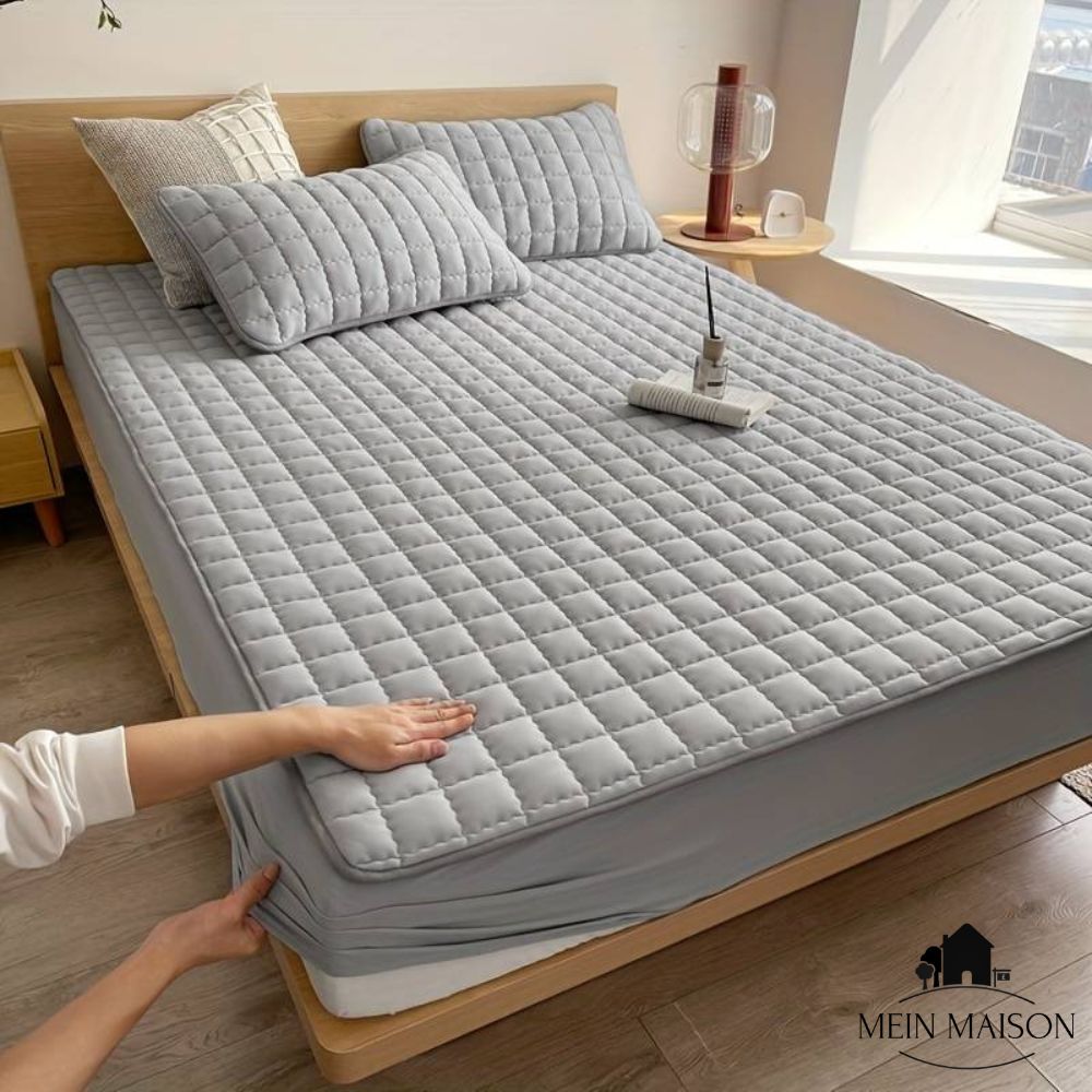 Grey mattress protector fitted on a wooden bed frame