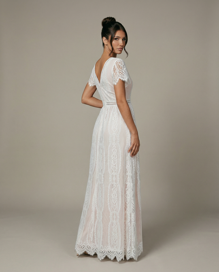 Back view of a model showcasing the flowing skirt and detailed lace back of the white maxi gown.