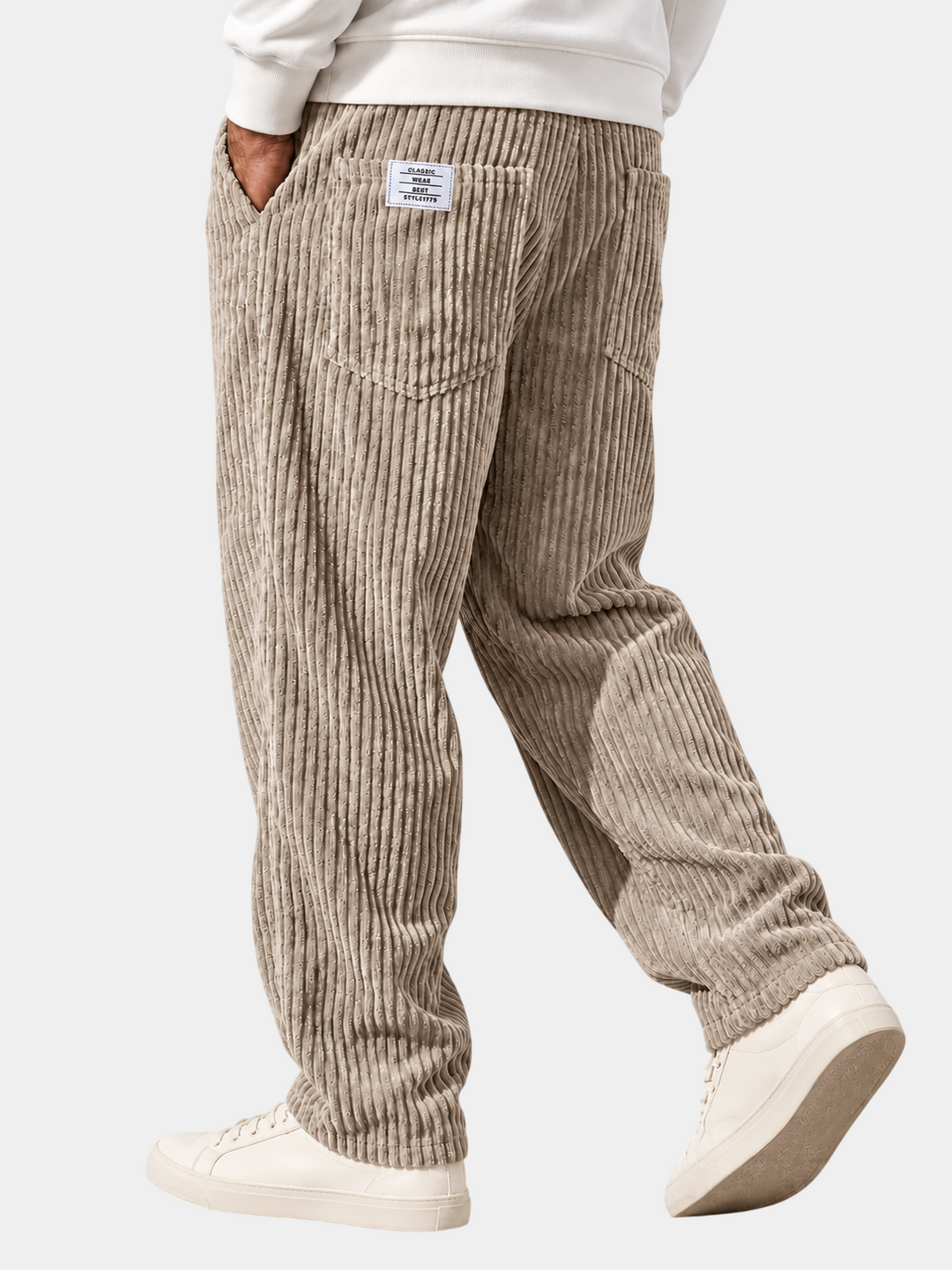 Back view of a man wearing textured relaxed-fit trousers in khaki with side pockets and casual sneakers