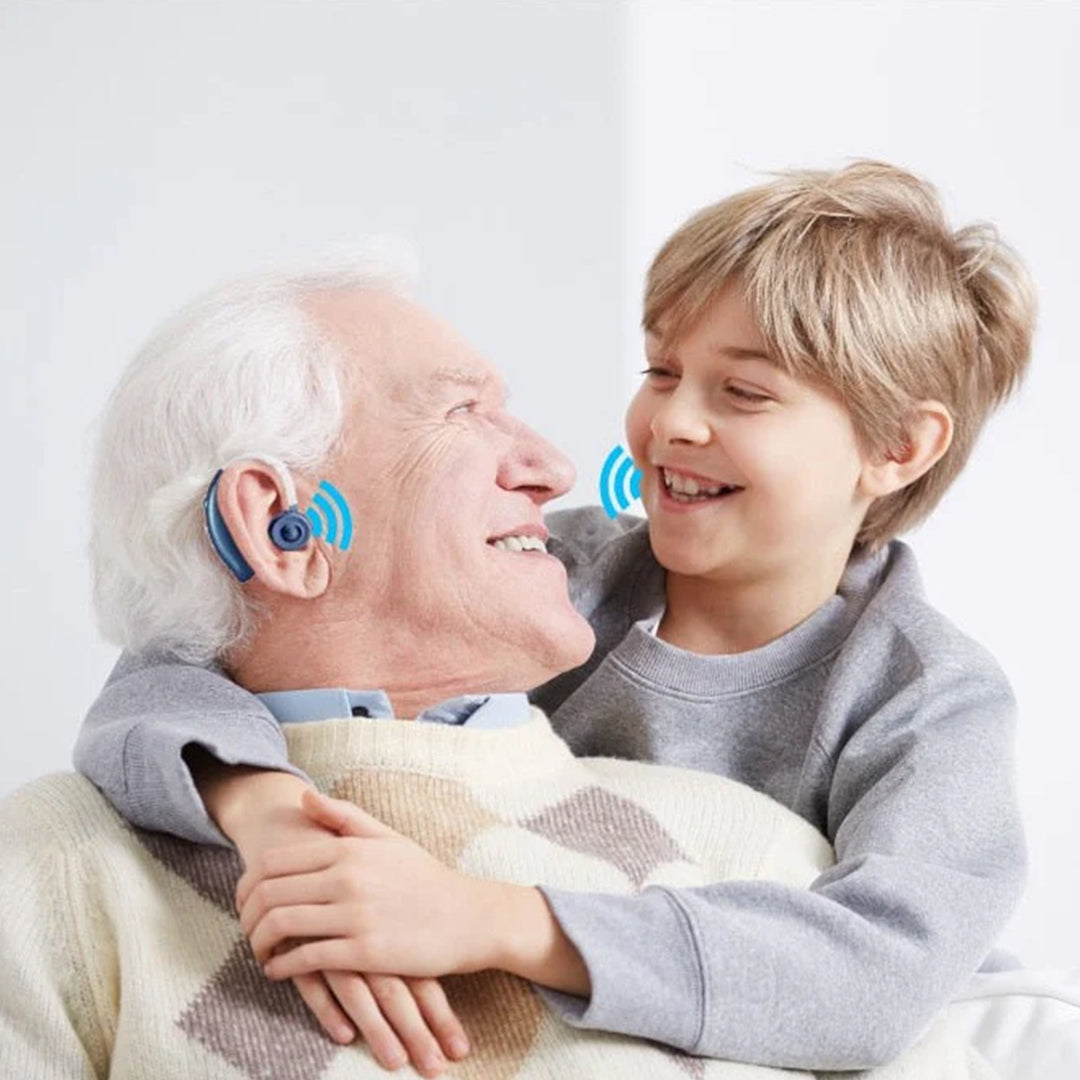 Elderly man smiling while embracing his grandchild while wearing a blue behind-the-ear sound amplifier