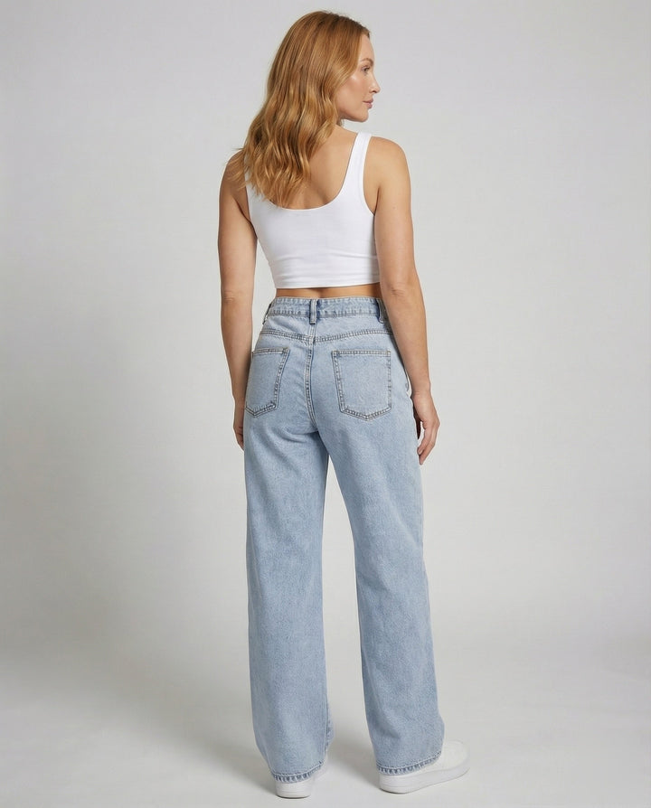 Model wearing women's vintage wash flared jeans and white crop top back view