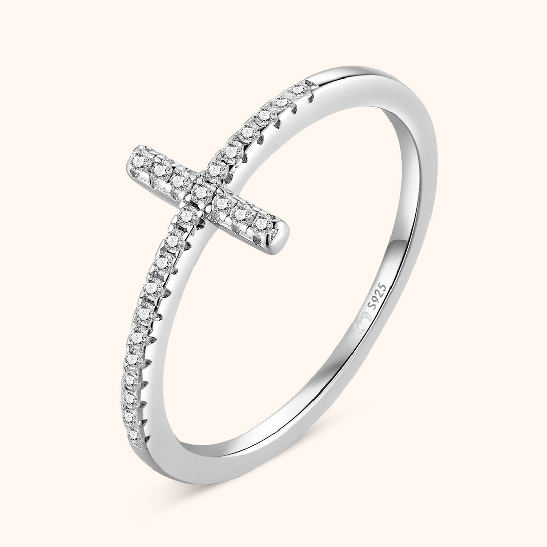 Silver zirconia cross ring displayed against a soft neutral background