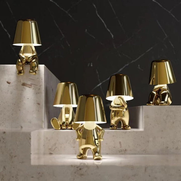 Gold metallic sculptural table lamps arranged on a tiered display surface