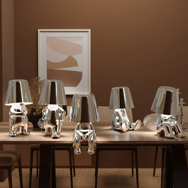 Silver figure table lamps showcasing different poses on a wooden dining table