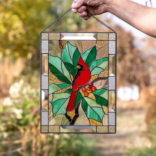 Person holding rectangular botanical sun catcher with cardinal bird design