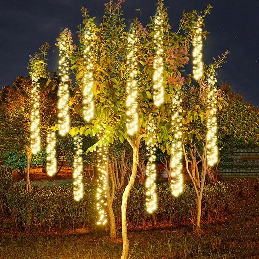 Cometfall warm white LED string lights hanging in an outdoor tree at night