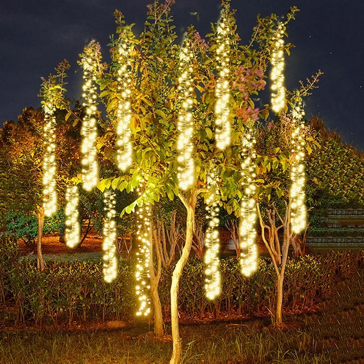 Cometfall warm white LED string lights hanging in an outdoor tree at night