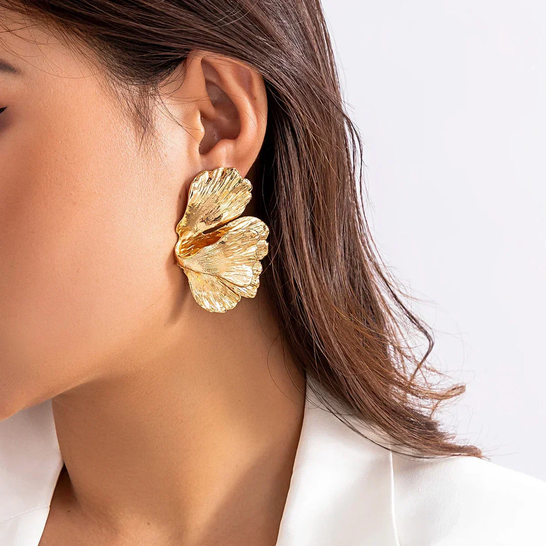 Side profile view of gold petal drop earrings on ear