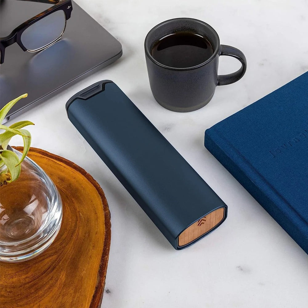 Sleek blue pill container resting on a wooden desk next to a coffee cup