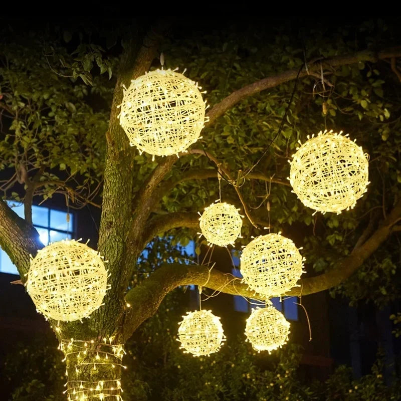 Sphere rattan string lights hanging in a tree at night, glowing brightly