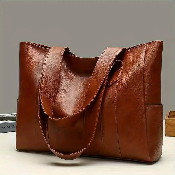 Coffee brown women's shoulder bag displayed on a table