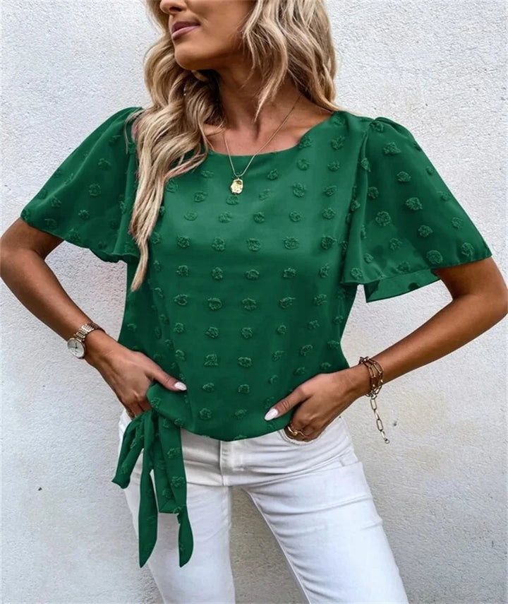 Woman wearing green Beatriz blouse with short sleeves and textured floral pattern