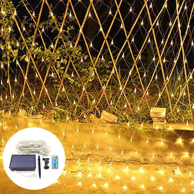Solar fairy light net glowing softly over lush garden bushes at dusk