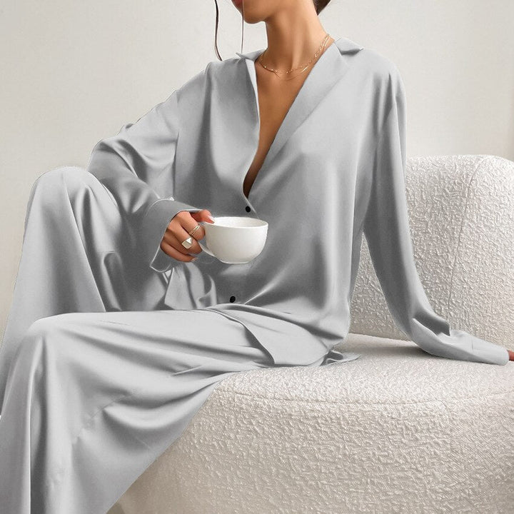Model seated wearing a grey satin pyjama set with lapel collar