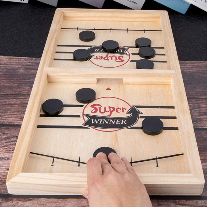 Close-up of wooden table hockey board showing pucks and elastic sling launcher mechanism
