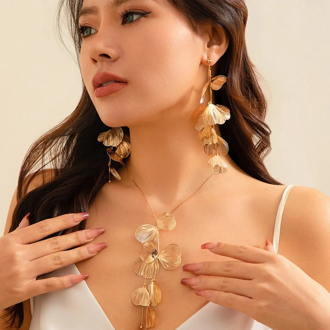 Model wearing cascading leaf pendant necklace and long drop earrings set