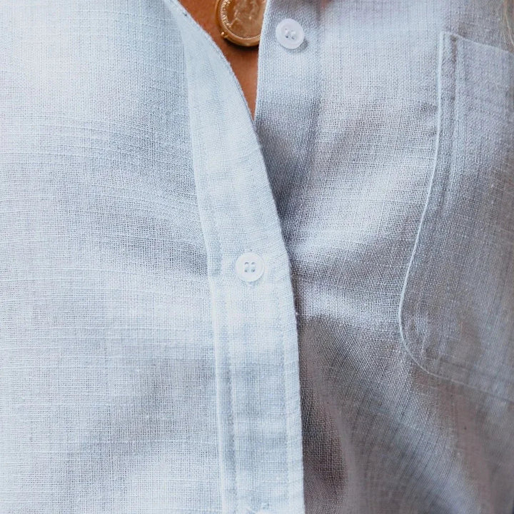 Close-up view of the button placket and pocket detail on the light blue blouse