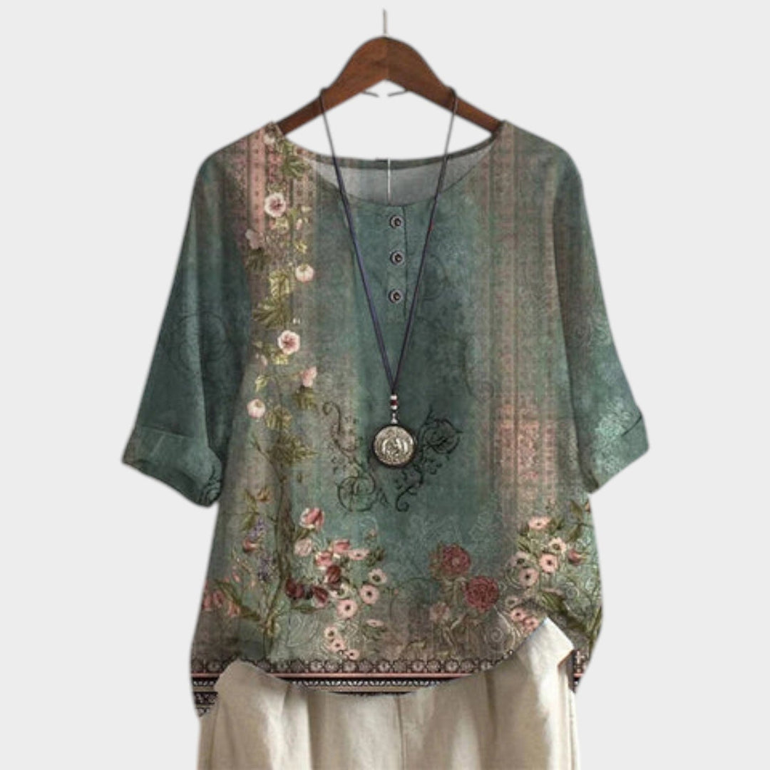 Women's green boho floral short sleeve blouse on hanger with decorative necklace