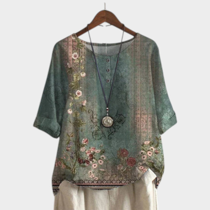 Women's green boho floral short sleeve blouse on hanger with decorative necklace