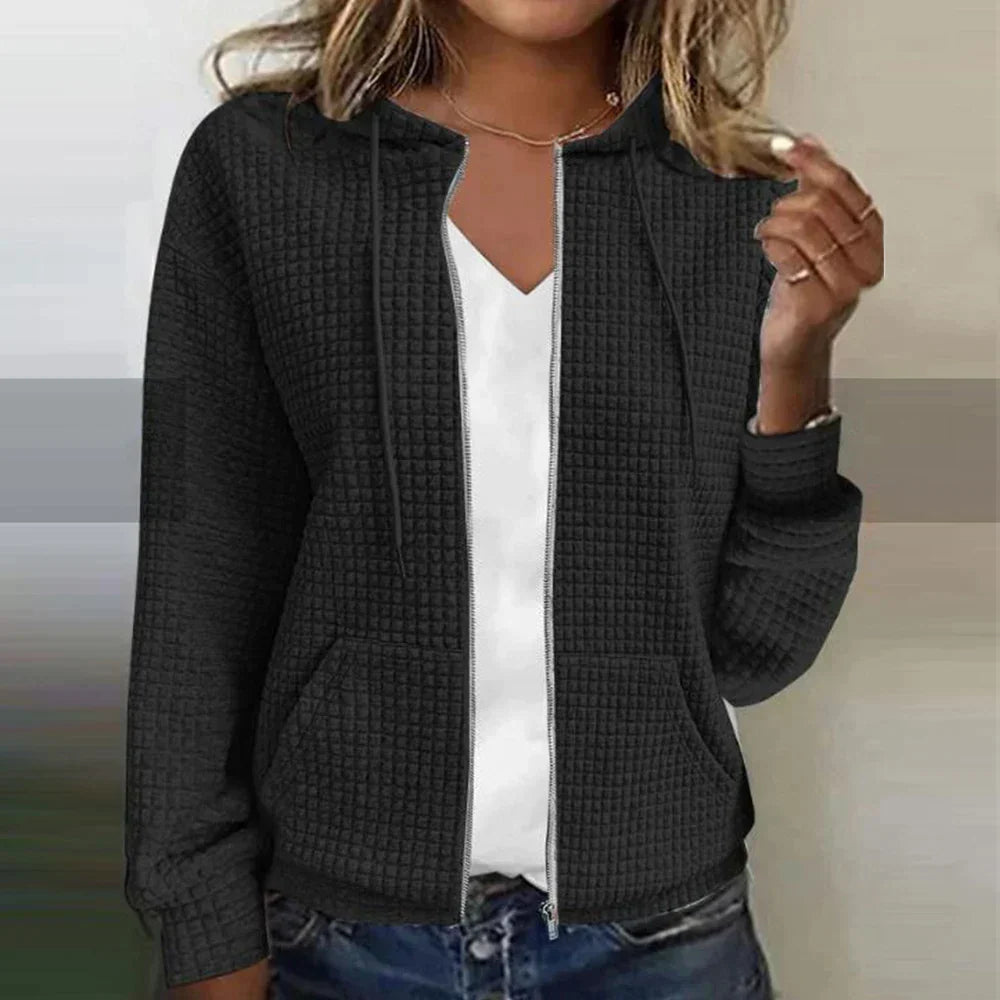 Woman wearing black textured zip-up hooded jacket with front pockets