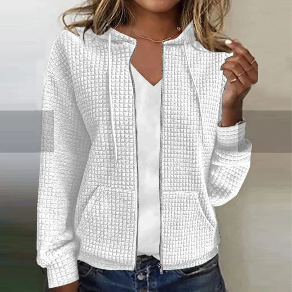 Woman wearing white textured zip-up hooded jacket paired with jeans