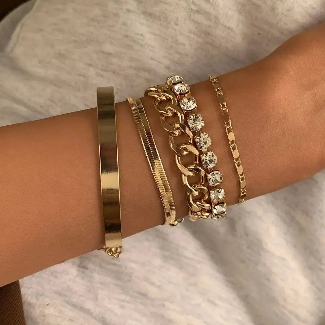 Womens gold metal chain stackable bracelet set on white background